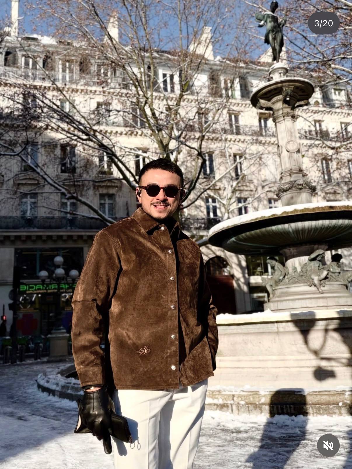 Jovian Mandagie wearing a brown suede jacket in a European city square